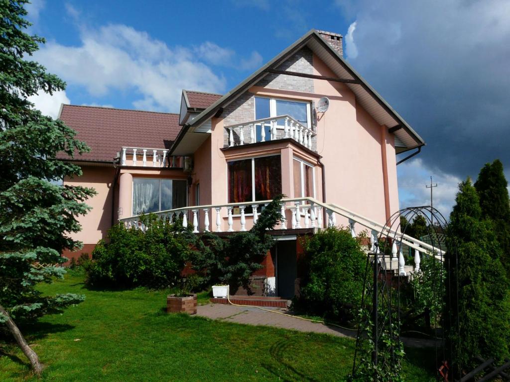 uma grande casa cor-de-rosa com uma varanda num quintal em Villa Vivian em Szczecin