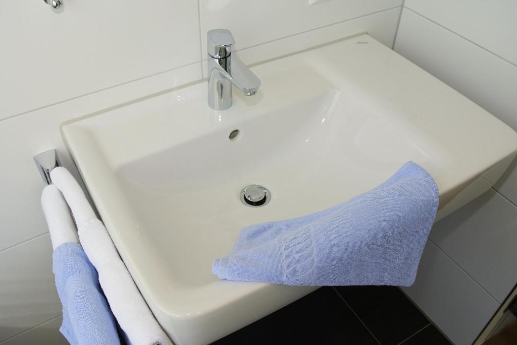 a white bathroom sink with a blue towel on it at Haus am Blauenbach in Schliengen
