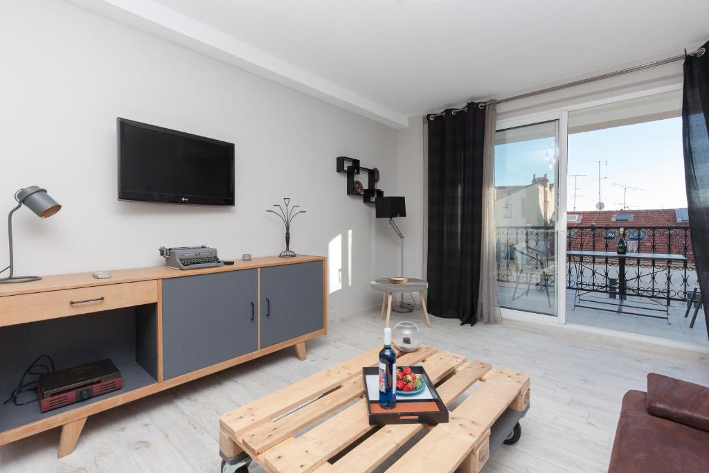 un salon avec une télévision et une table basse dans l'établissement Loft 3 pièces duplex 3 étoiles calme centre ville à 5 mn des plages et palais, à Cannes