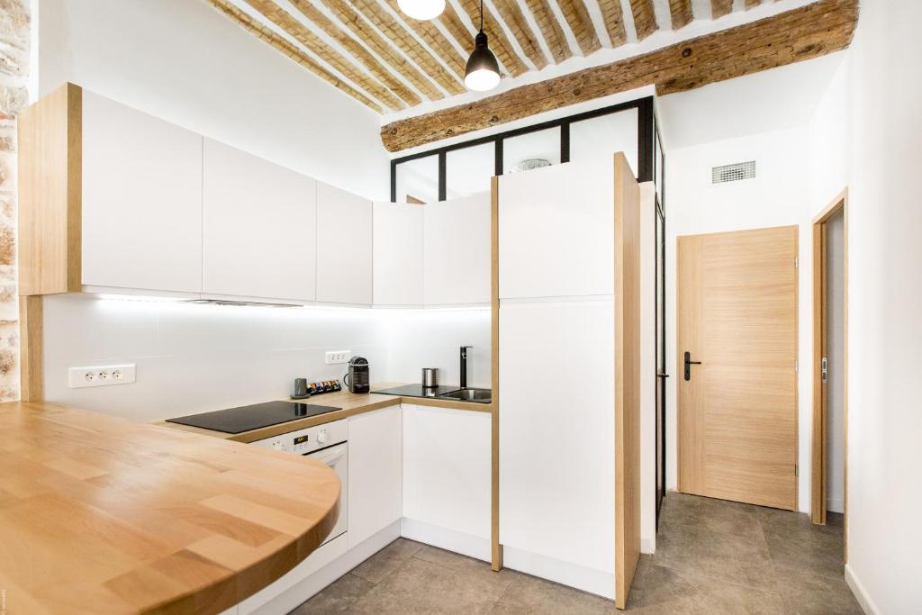 アンティーブにあるCharming Appartmentのキッチン(白いキャビネット、木製カウンタートップ付)