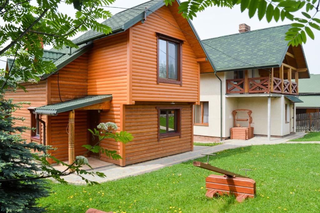 una casa de madera con césped delante en Zolota Rybka, en Skhidnytsya