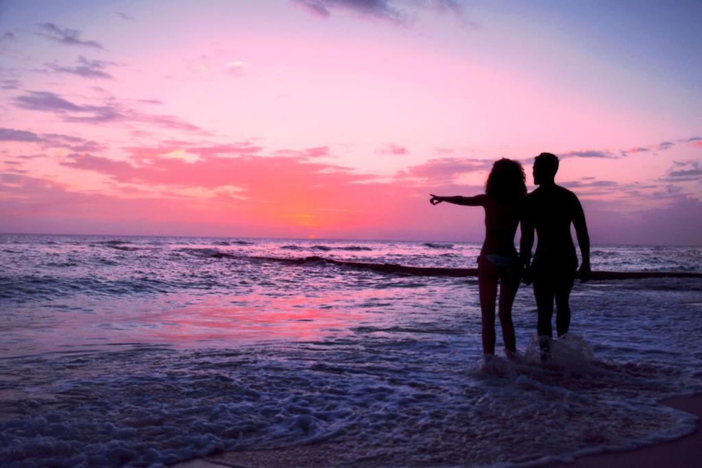 a couple standing on the beach watching the sunset at Sugar Bay Barbados - All Inclusive in Bridgetown