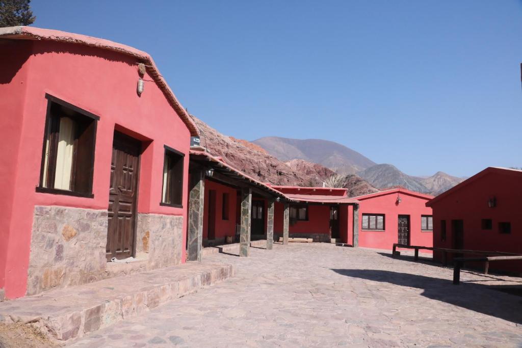 a row of red buildings with mountains in the background at Hostal Paseo de los Colorados in Purmamarca