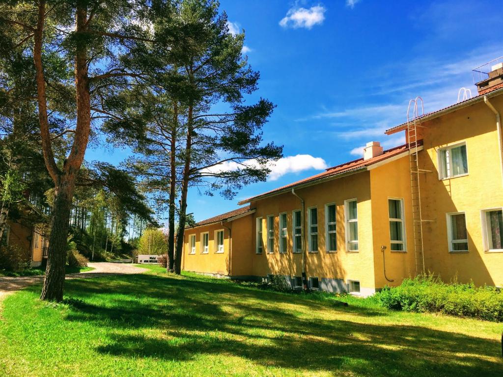 un antiguo edificio con árboles delante de él en Hostel Vanha Koulu en Monola