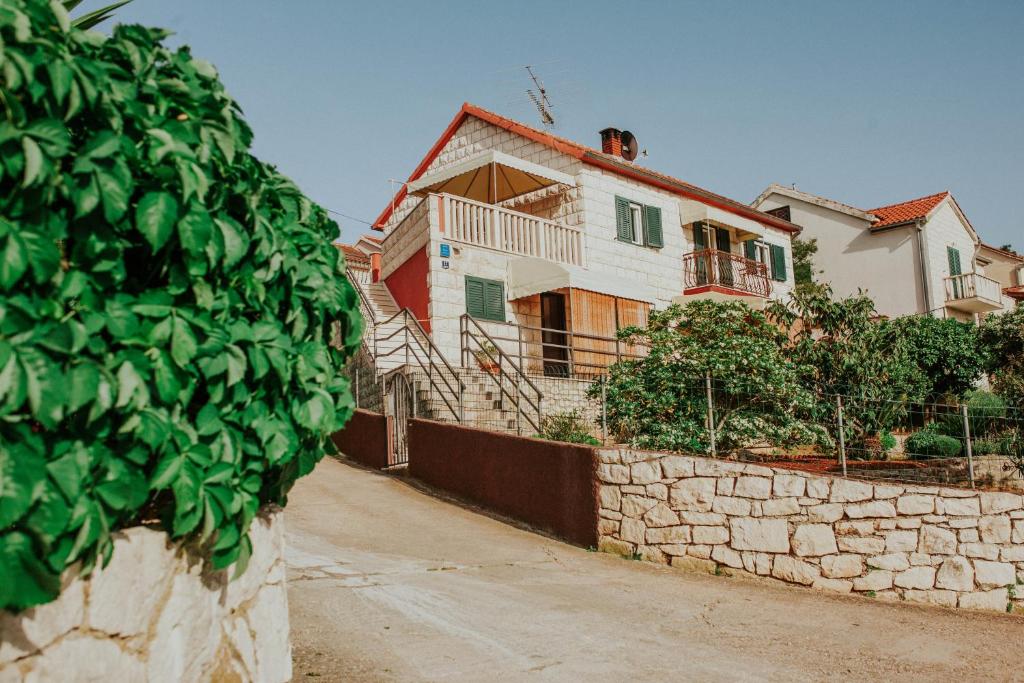 a house with a stone wall next to a street at Apartments Doulos in Splitska