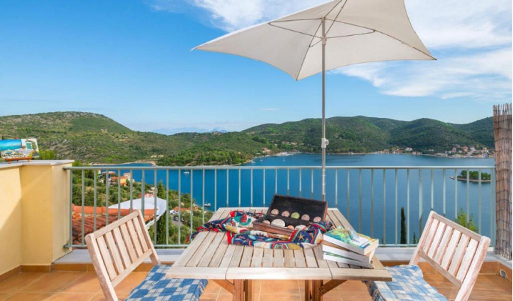 eine Terrasse mit einem Tisch und einem Sonnenschirm auf dem Balkon in der Unterkunft Odysseion Apartments in Vathy