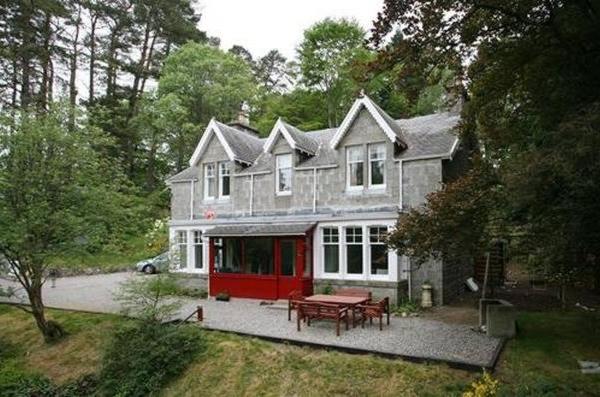 una casa grande con una mesa de picnic delante de ella en Netherwood House, en Newtonmore