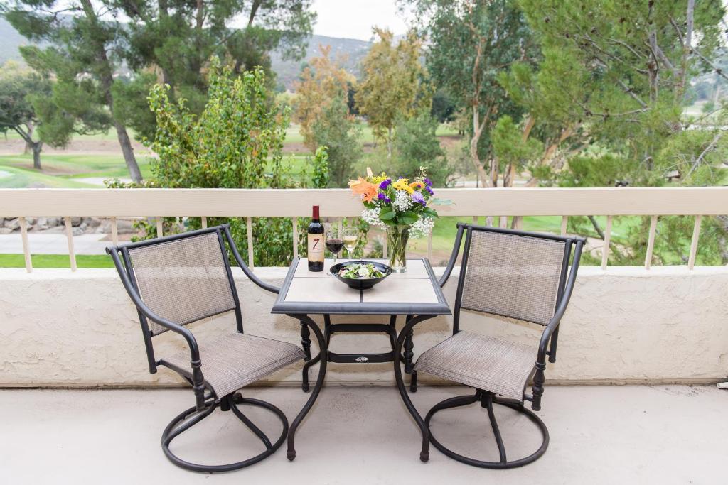 - une table avec 2 chaises et une bouteille de vin sur le balcon dans l'établissement San Vicente Golf Resort, à Ramona