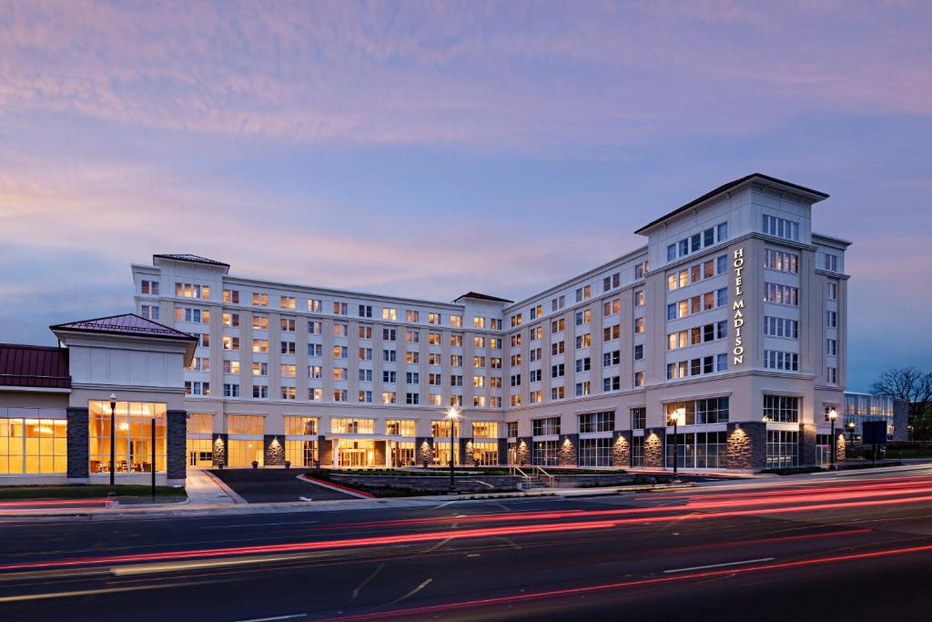 a large white building on a city street at night at Hotel Madison & Shenandoah Conference Ctr. in Harrisonburg