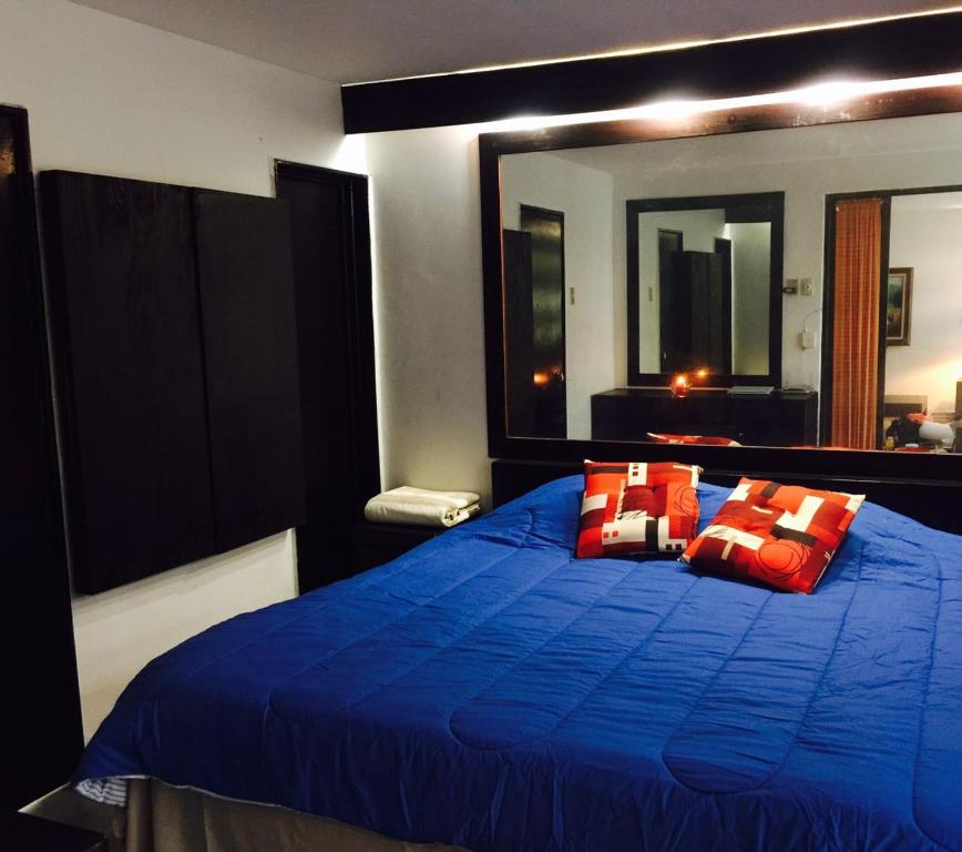 um quarto com uma cama azul e almofadas vermelhas em CDMX - Great Location at Napoles em Cidade do México