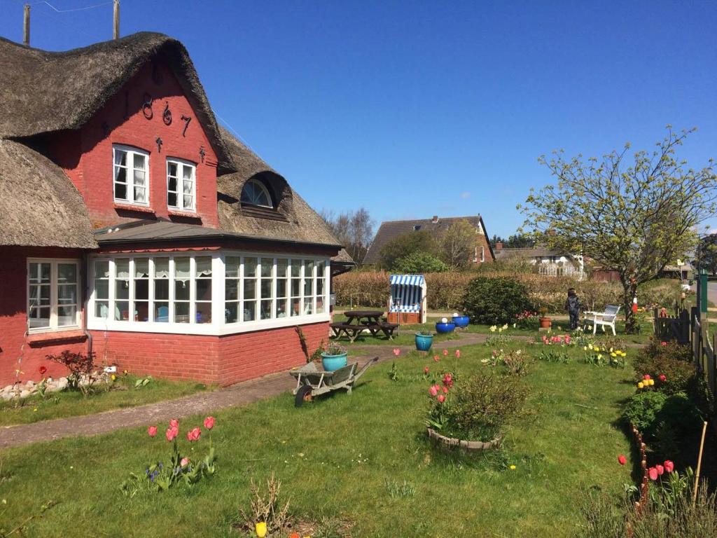 a red house with a yard with flowers in it at Hüs Sanskiin Ferienwohnung *Hopelfask* in Süddorf