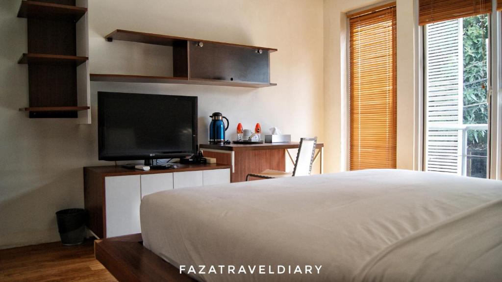 Un dormitorio con una cama y un televisor de pantalla plana. en FLAT06 cipete, en Yakarta