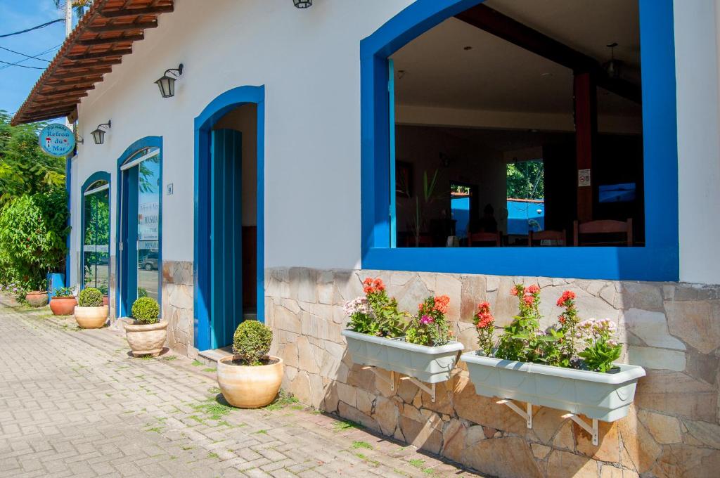 um edifício azul e branco com vasos de plantas num passeio em Refron du Mar Pousada Paraty em Paraty