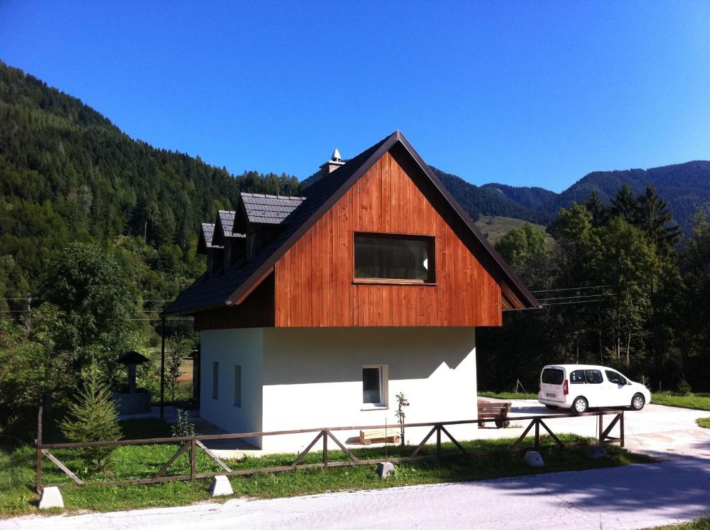 a house with a wooden roof and a van parked in front at Apartments Podkoren 82 in Kranjska Gora