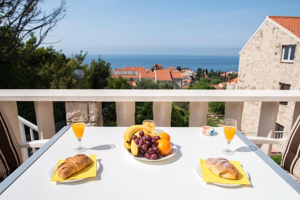 een witte tafel met een schaal fruit en sinaasappelsap bij De Luxe Apartment Mediteran 3**** in Dubrovnik