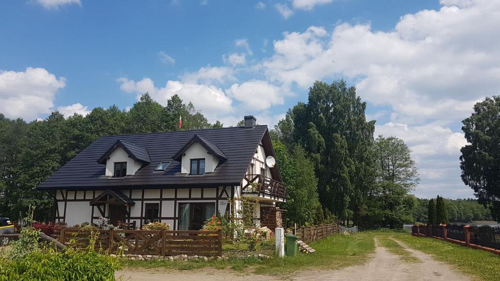 une maison avec un toit noir sur un chemin de terre dans l'établissement Przystań Kapitanat, à Szczecinek