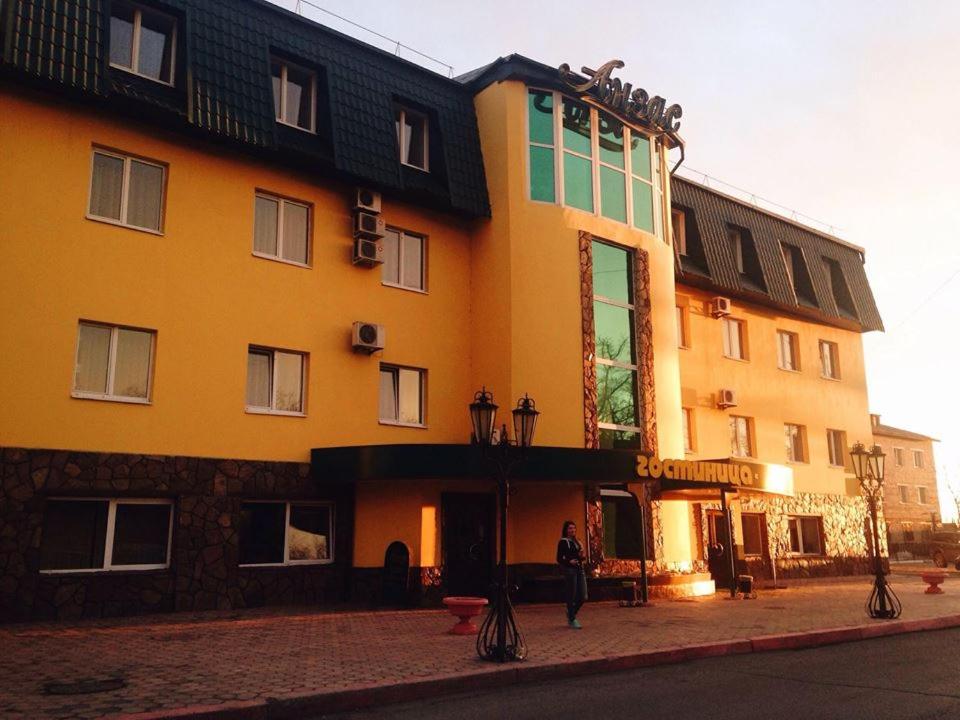 una persona parada frente a un gran edificio amarillo en Hotel Anzas, en Abakán