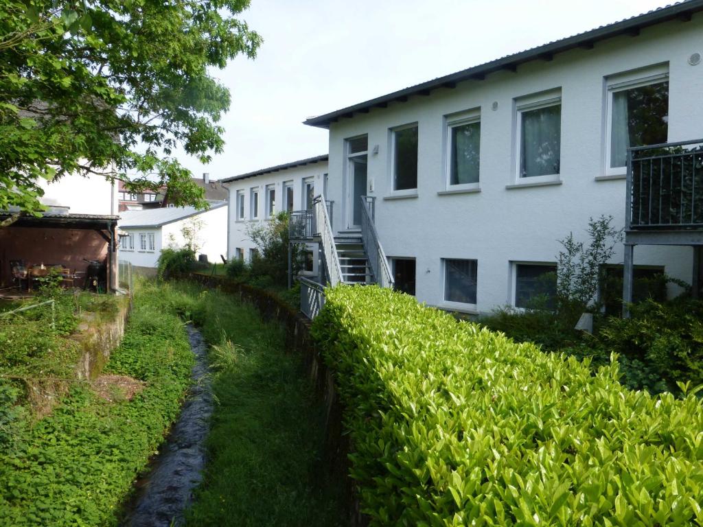 ein Haus mit Hecke neben einem Gebäude in der Unterkunft Ferienwohnung an der Kimbach 1 in Bad König