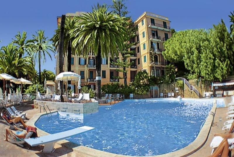 a beach with a pool and a large building at Grand Hotel De Londres in Sanremo
