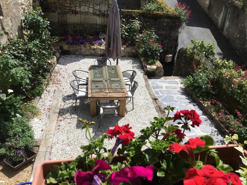 un jardín con mesa, sillas y flores en La douceur Angevine, en Montreuil-Bellay