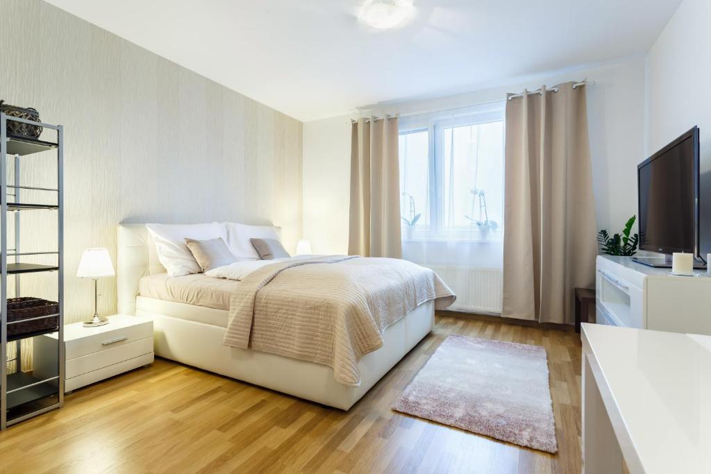 a white bedroom with a bed and a television at Golden Apartments Rezidence Nová Karolina in Ostrava