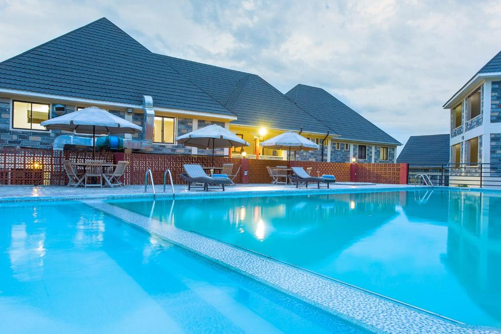 basen z leżakami i parasolami przed budynkiem w obiekcie Epashikino Resort & Spa w mieście Gilgil