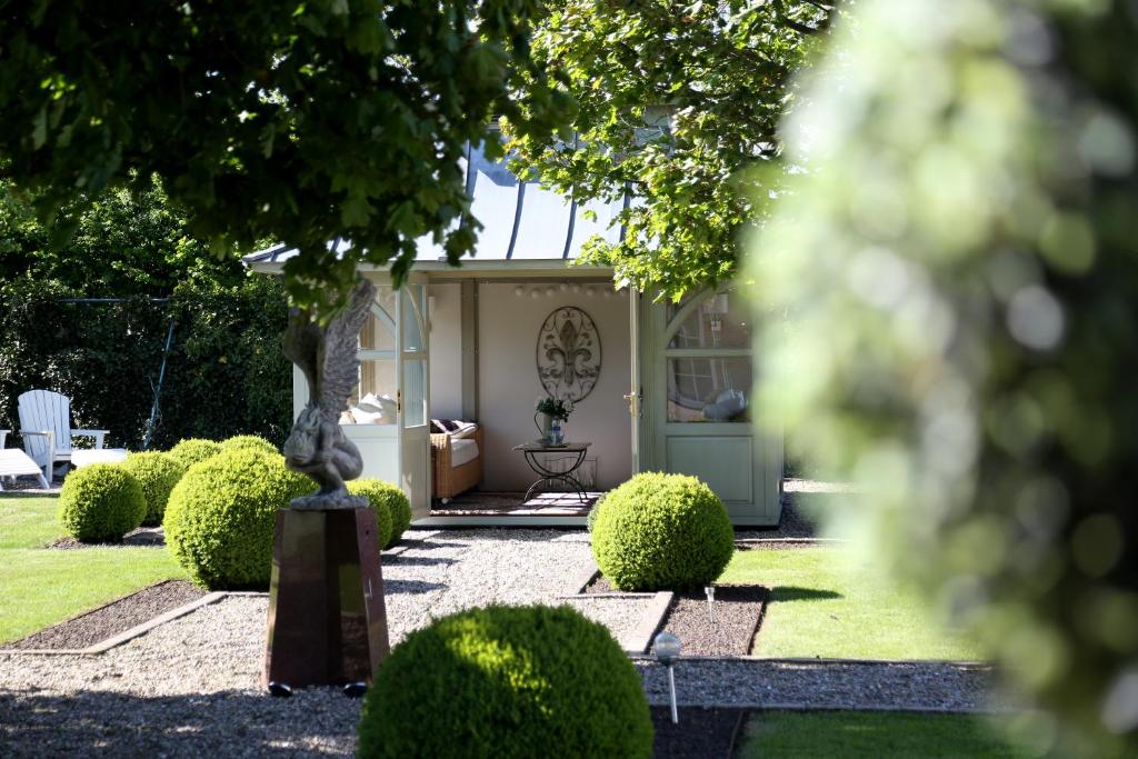 un jardín con una casa con un árbol y arbustos en Green Cottage, en Büdelsdorf