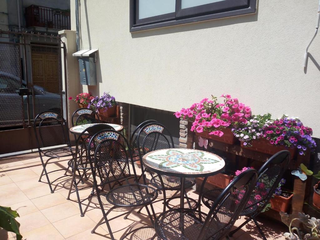 eine Gruppe von Tischen und Stühlen mit Blumen auf einer Terrasse in der Unterkunft Eurelios in Adrano