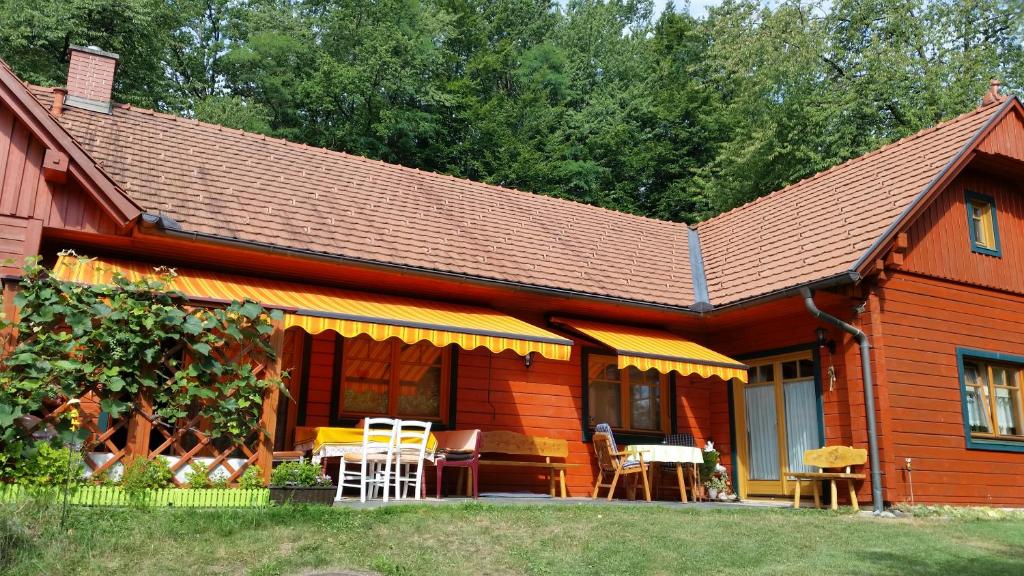 une maison en bois avec des tables et des chaises devant elle dans l'établissement Ferienwohnung Nostalgie, à Ehrenhausen