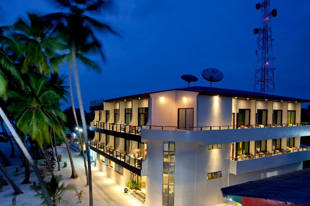 a building on the beach with palm trees at night at Kaani Beach Hotel in Maafushi