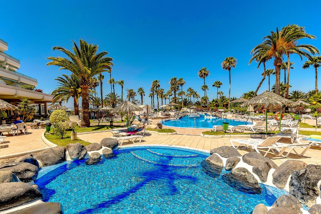 a pool at a resort with palm trees at Apartamento Altamira in Adeje