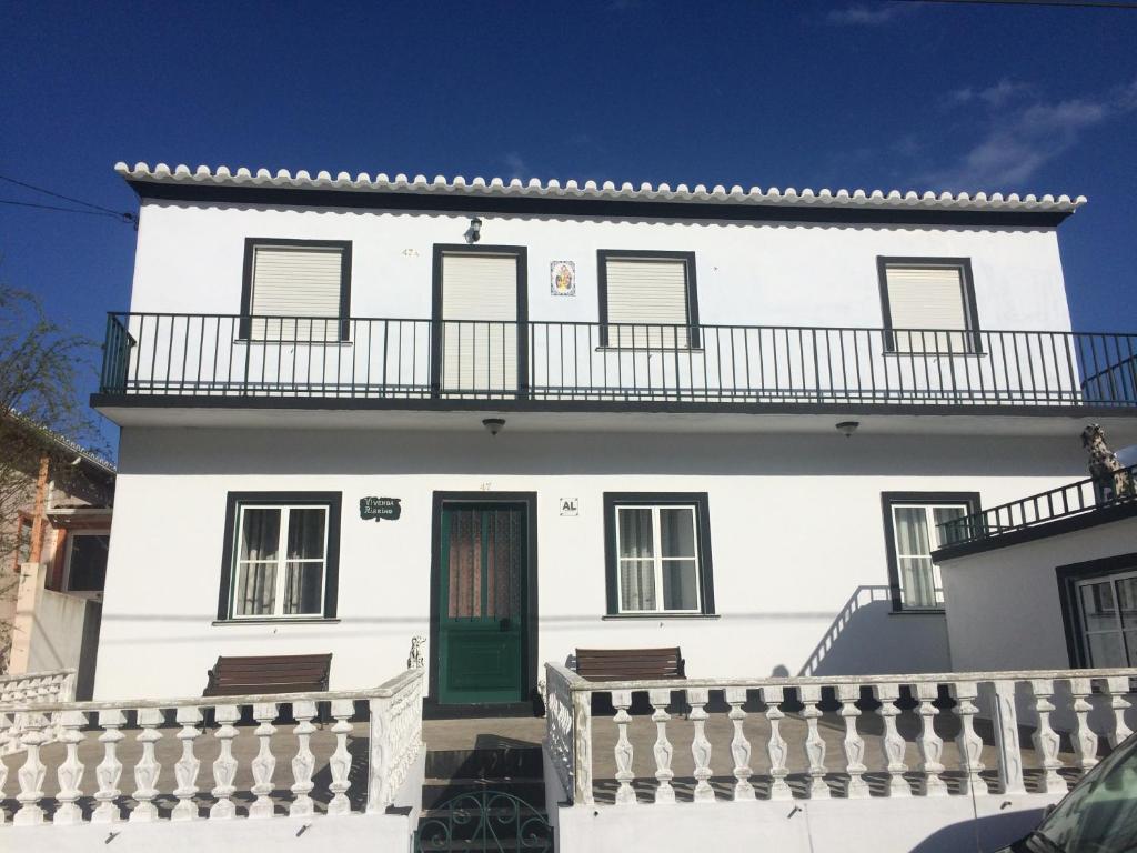 a white house with a green door and a balcony at Casa Sousa Ribeiro in Praia da Vitória