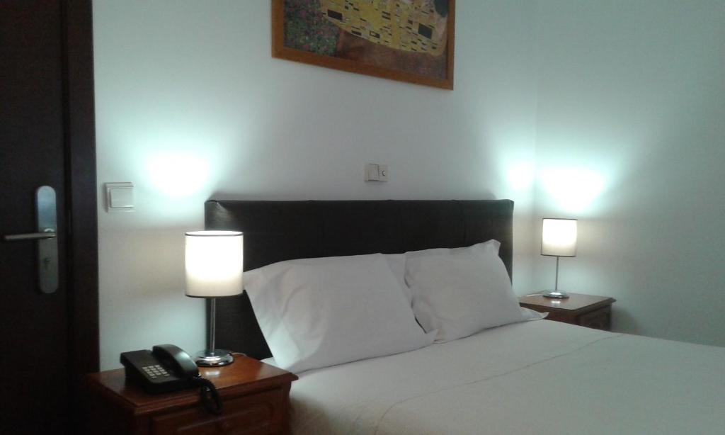um quarto com uma cama com 2 candeeiros e um telefone em Hotel Tic Tac em Bragança