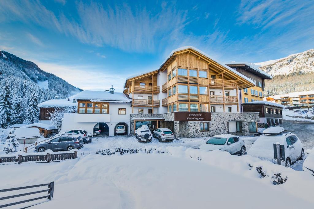 a ski lodge with cars parked in the snow at Residence Crazzolara in La Villa
