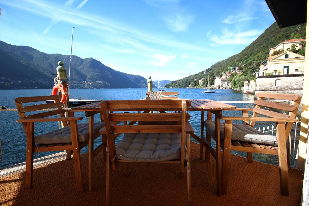 a table and chairs on a deck with a view of the water at Darsena di Riva Grande in Moltrasio