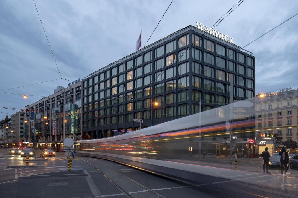 ein Gebäude in einer Stadtstraße mit einem Bus in der Unterkunft Warwick Geneva in Genf