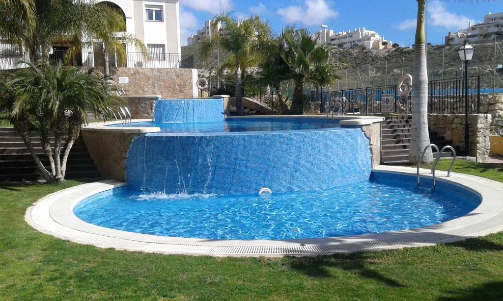ムチャメルにあるApartmento Rosaledaの青いプール(芝生の中に噴水あり)