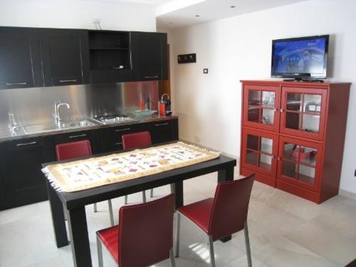 a kitchen with a table with chairs and a tv at Sillia Appartamenti in Pinzolo