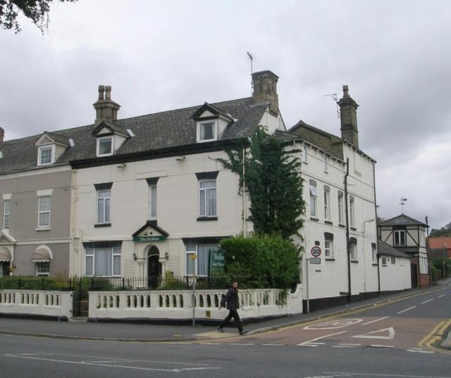 a man walking down a street in front of a white building at The Hollies Guest House in Lincoln