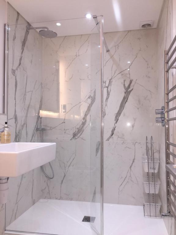 y baño con ducha acristalada y lavamanos. en Lexham Gardens Lodge 5 en Londres