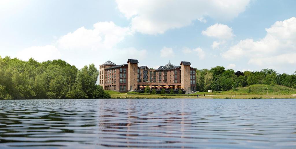 een groot gebouw aan de rand van een waterlichaam bij Parkhotel Horst - Venlo in Horst