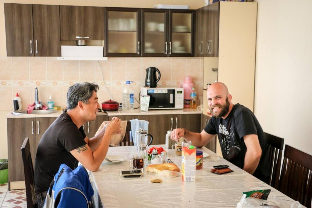 dos hombres sentados en una mesa en una cocina en Hostel Nice, en Karakol