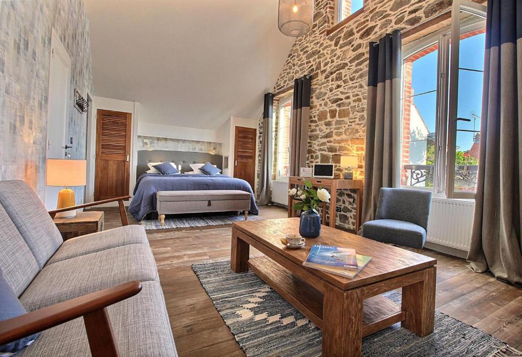 ein Wohnzimmer mit einem Bett, einem Sofa und einem Tisch in der Unterkunft La Cotentine Maison d'Hôtes in Saint-Pair-sur-Mer