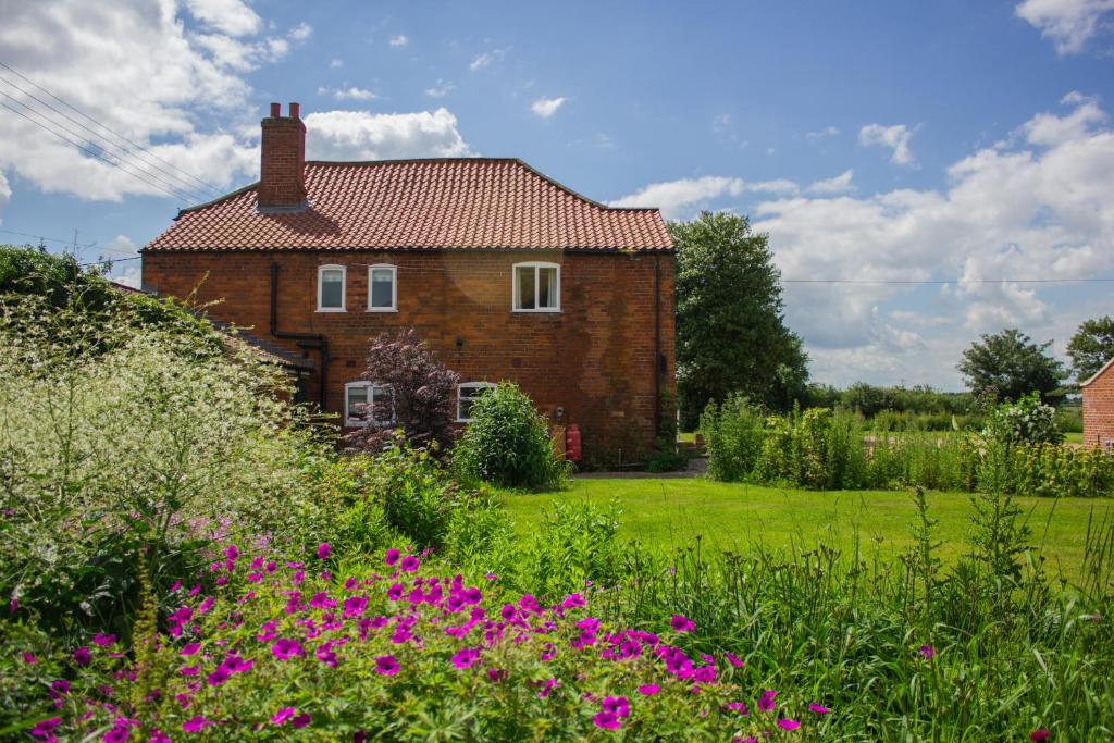 una casa con un campo de flores delante de ella en Holly Farm en Doddington