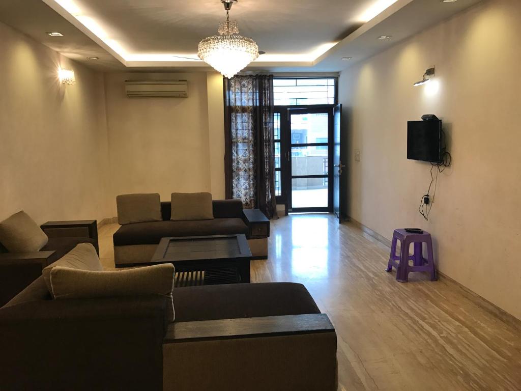 Spacious 3bhk apartment! في نيودلهي: غرفة معيشة مع كنبتين وتلفزيون