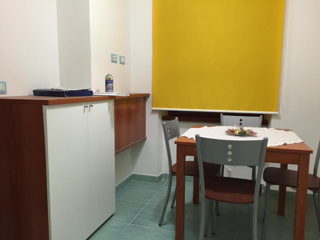 une cuisine avec une table et des chaises et un mur jaune dans l'établissement Joseph Apartment, à San Benedetto del Tronto