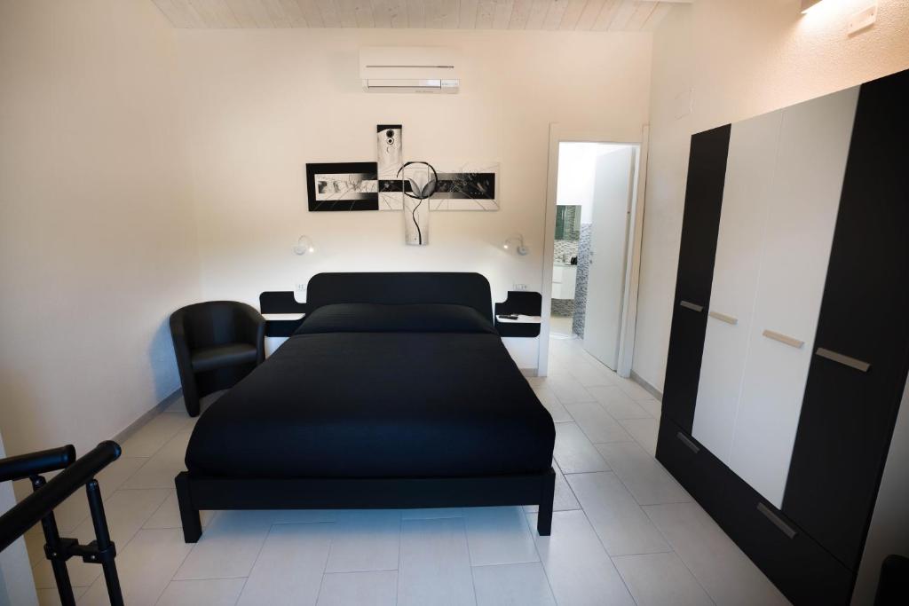 a bedroom with a black bed and a chair at The House On The River in Bosa