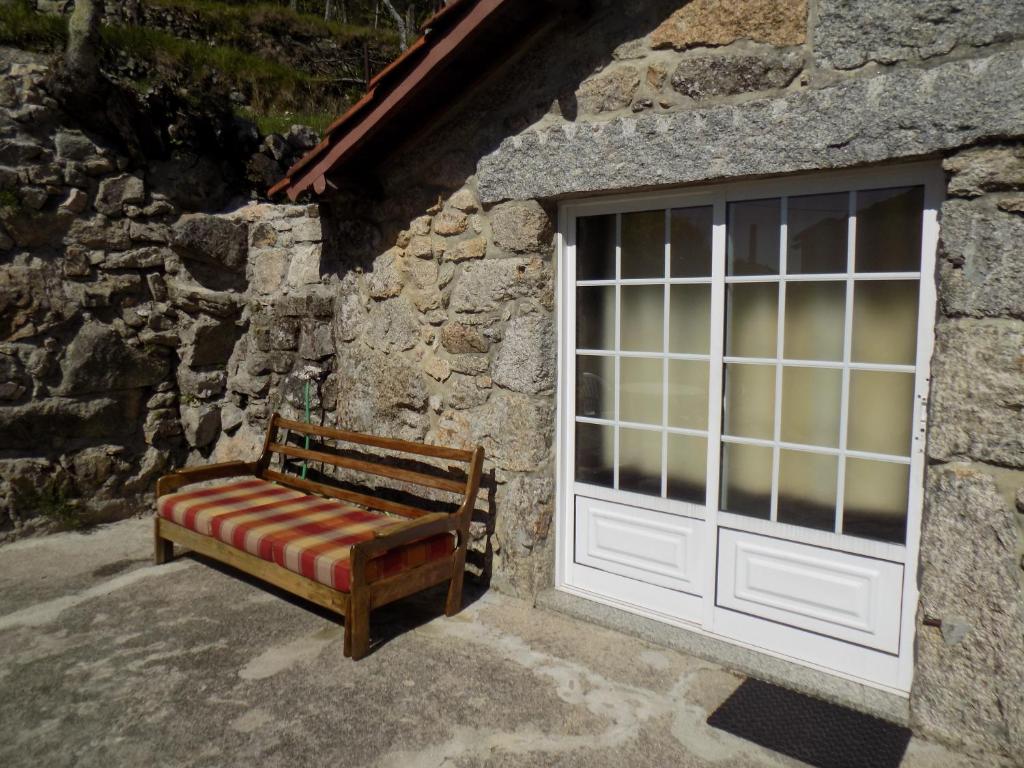 a bench in front of a stone building with a door at Casa da Venda in Covide