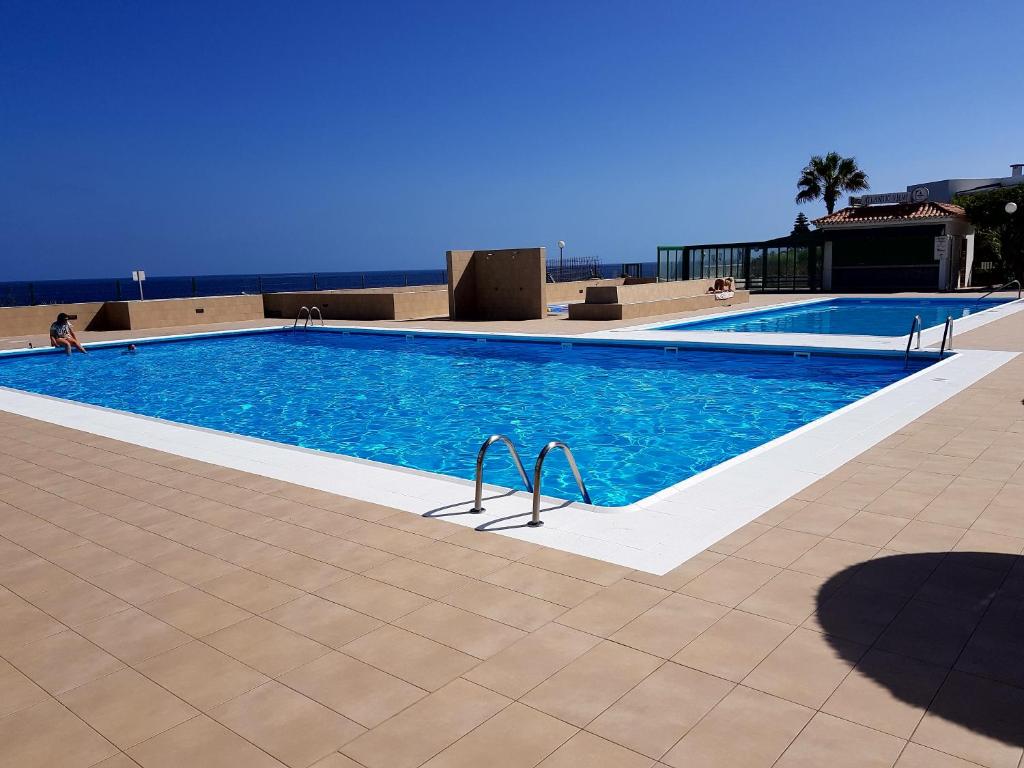 een groot zwembad met blauw water in een gebouw bij Apartment direkt am Meer in Costa Del Silencio
