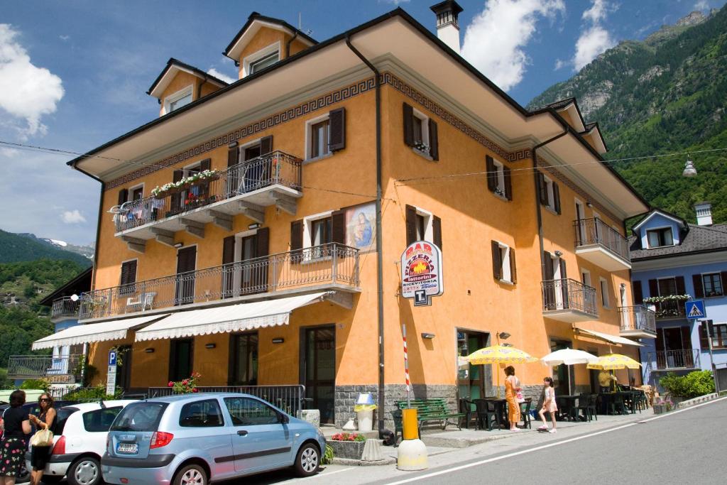 a yellow building with a car parked in front of it at Affittacamere Ca' Fattorini in Baceno